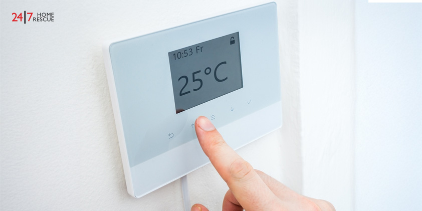Hand adjusting central heating thermostat for room temperature control