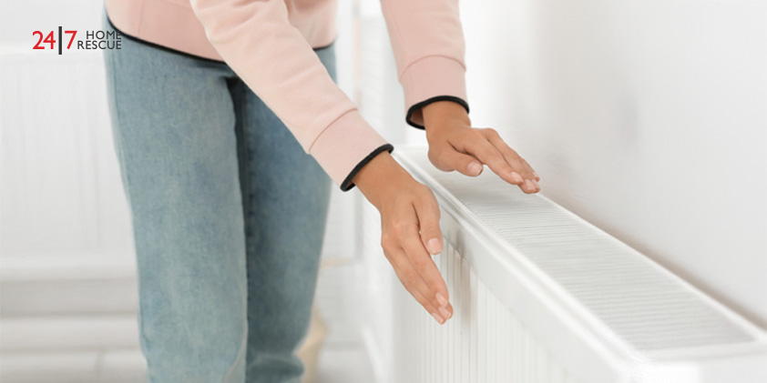 Woman warming her hands on a white heating radiator