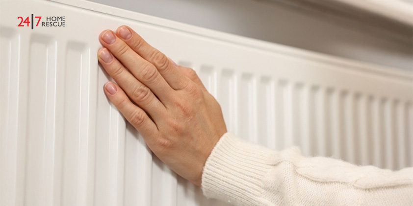 Woman warming hand near heating radiator at home