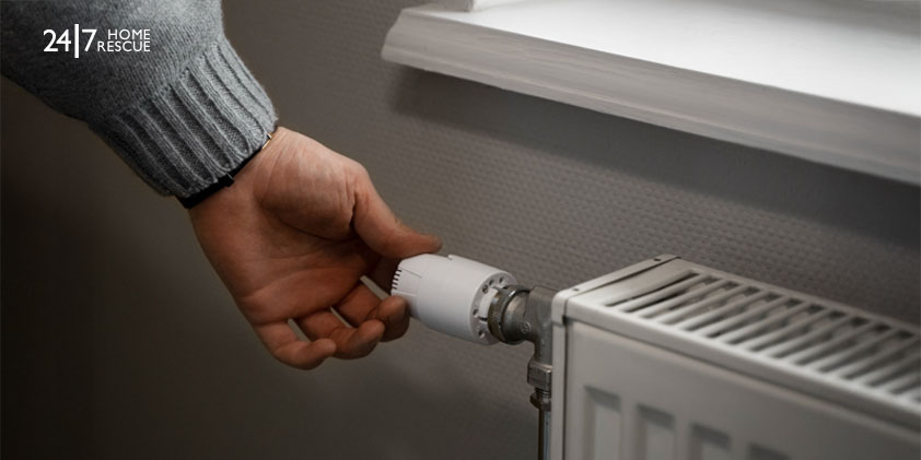 man adjusting radiator thermostat to control temperature