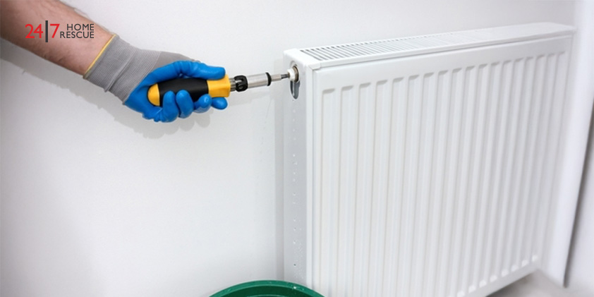 Technician using a tool to release air and water from a radiator air bleed valve