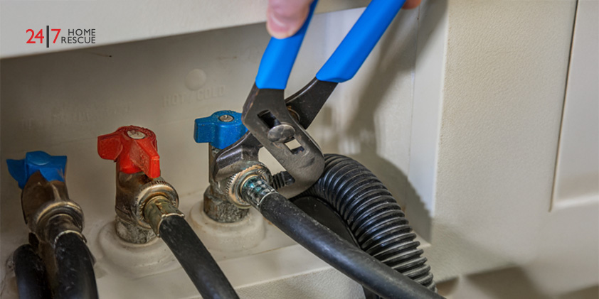 A plumber using a wrench to connect the water supply line to the shut-off valve of a washing machine