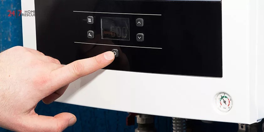 The man's finger turns on or off the start button of the heating system in the boiler room
