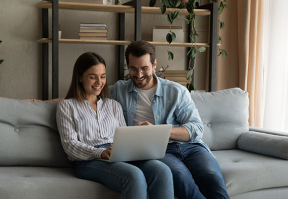A young family couple is using a laptop and discussing boiler cover options