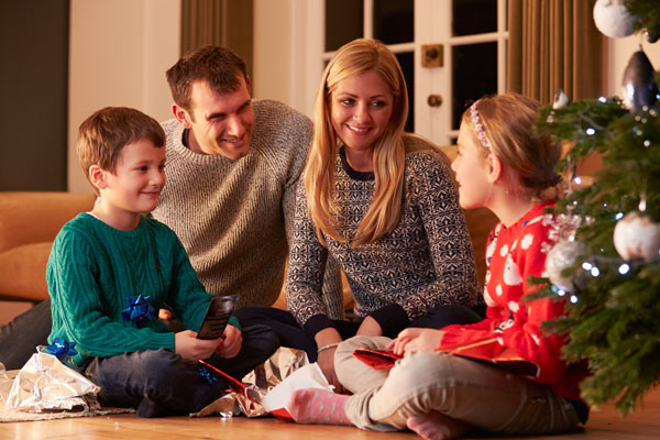 Family Unwrapping Gifts By Christmas Tree