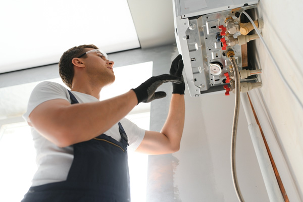 Gas engineer checking and cleaning a boiler during the inspection at home