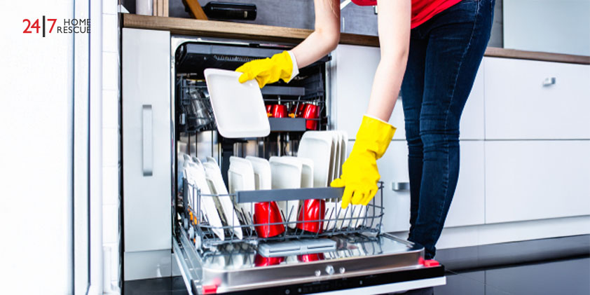 Young woman taking out clean dishes from dishwasher machine