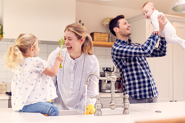 `Family having fun in kitchen doing washing up at sink together