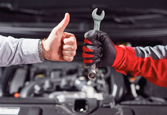 Person giving thumbs up in car repair area