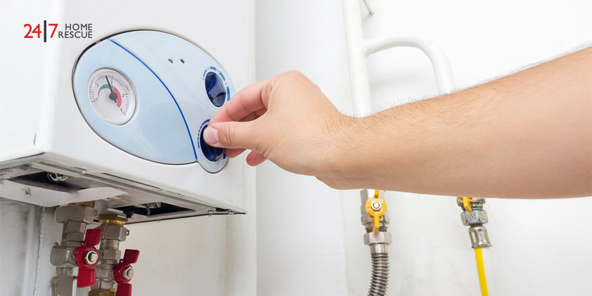 A man’s hand adjusting the control knob of a gas boiler within a household heating system