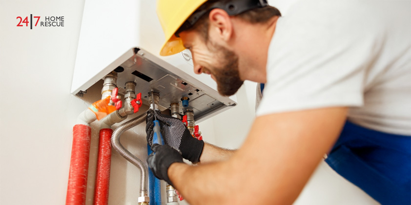 Close-up of a technician using a screwdriver while fixing a boiler in a heating system