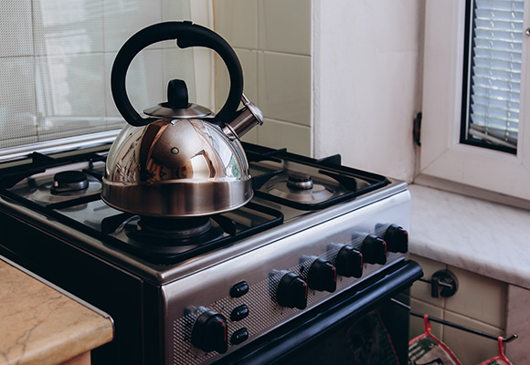 A kettle boils on a gas stove, emphasizing essential cooker insurance for home safety.