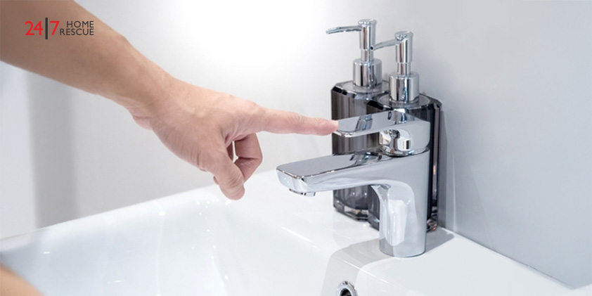 A male hand pointing at a chrome water faucet, checking the water tap.