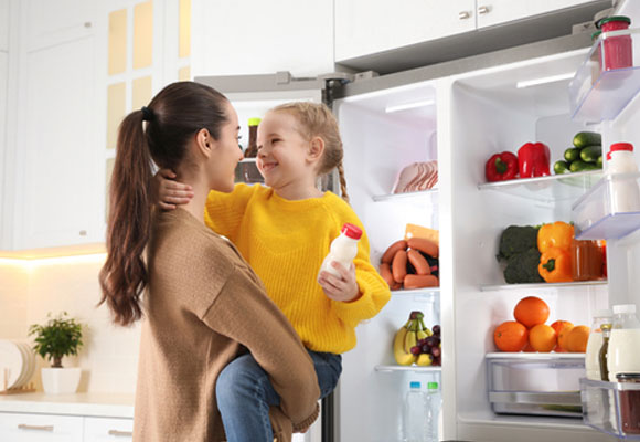 A mother and daughter beside a fridge-freezer