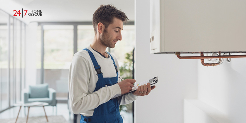 A boiler engineer using a checklist while inspecting a wall-mounted boiler during a home service visit.