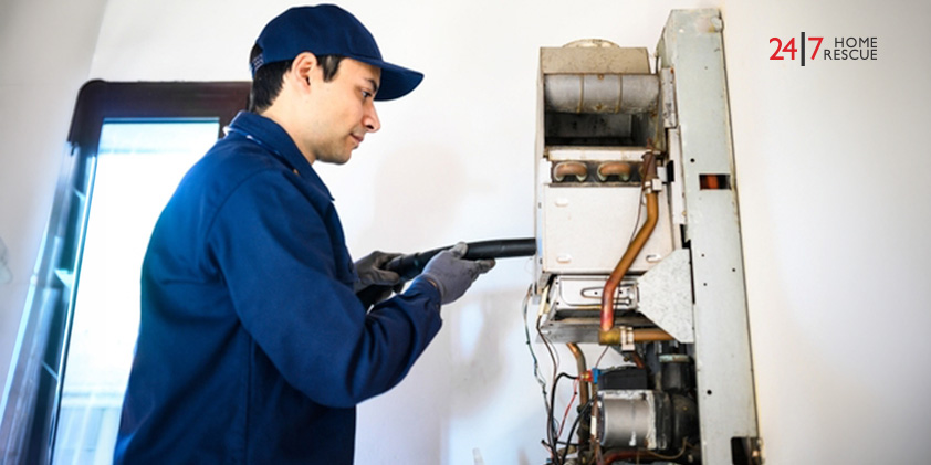 A heating engineer inspecting and servicing an open combi boiler unit in a home