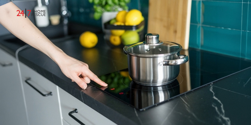 A person pressing the touch controls on an induction hob next to a saucepan
