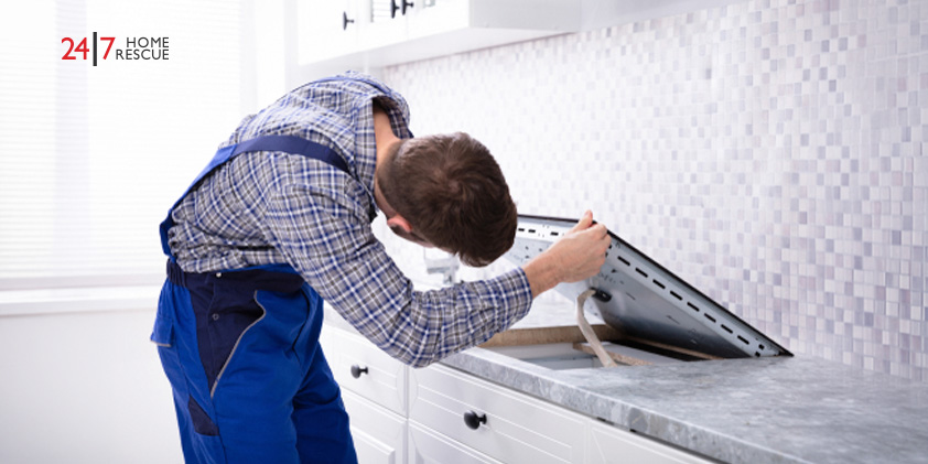 Engineer repairing an induction hob after lock or control panel issues in a modern kitchen