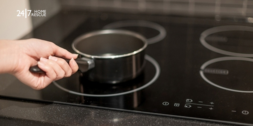 Hand placing a pan on an induction hob after unlocking the cooktop controls