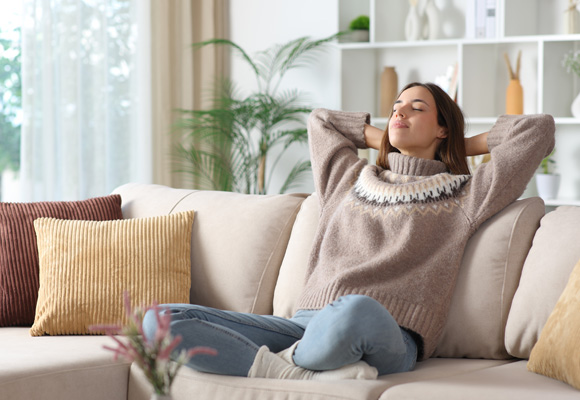 Woman relaxing comfortably on a sofa in a warm living room