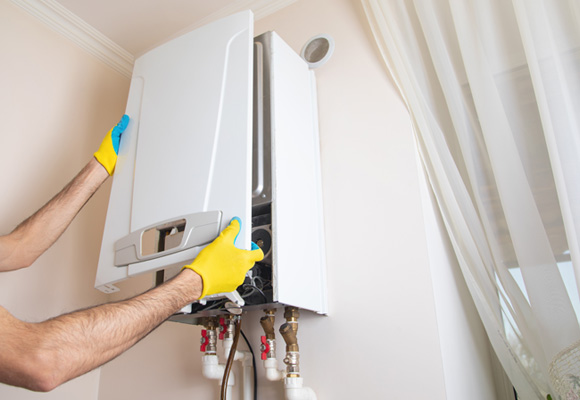 Engineer wearing gloves opening a boiler casing to inspect internal components