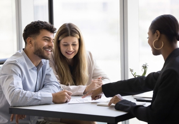 Couple reviewing and signing CP12 documents with an advisor at a desk