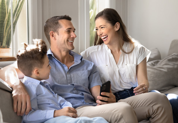 Family laughing together on a sofa at home